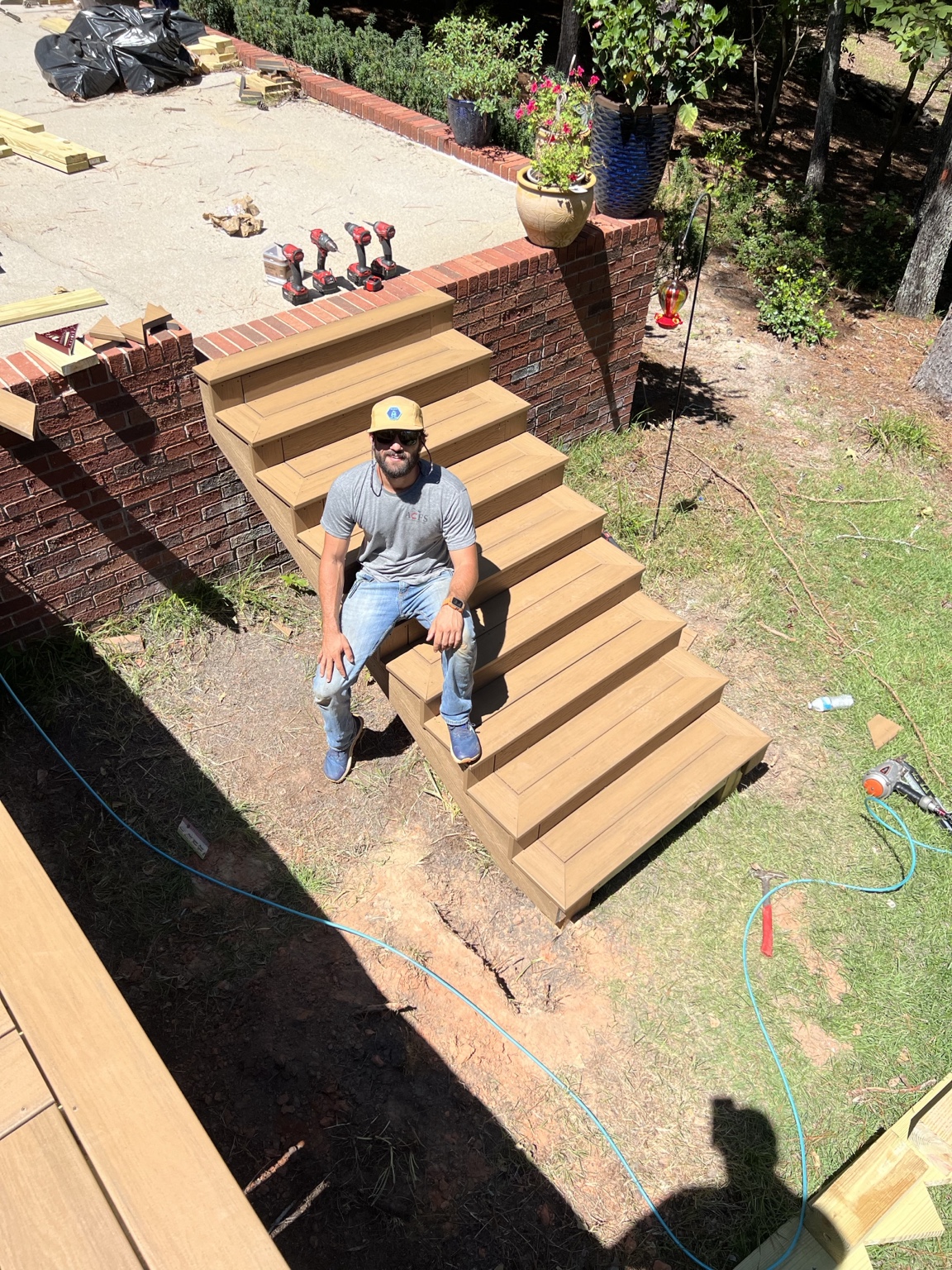 Chase seated on a newly built composite exterior stair run during deck construction