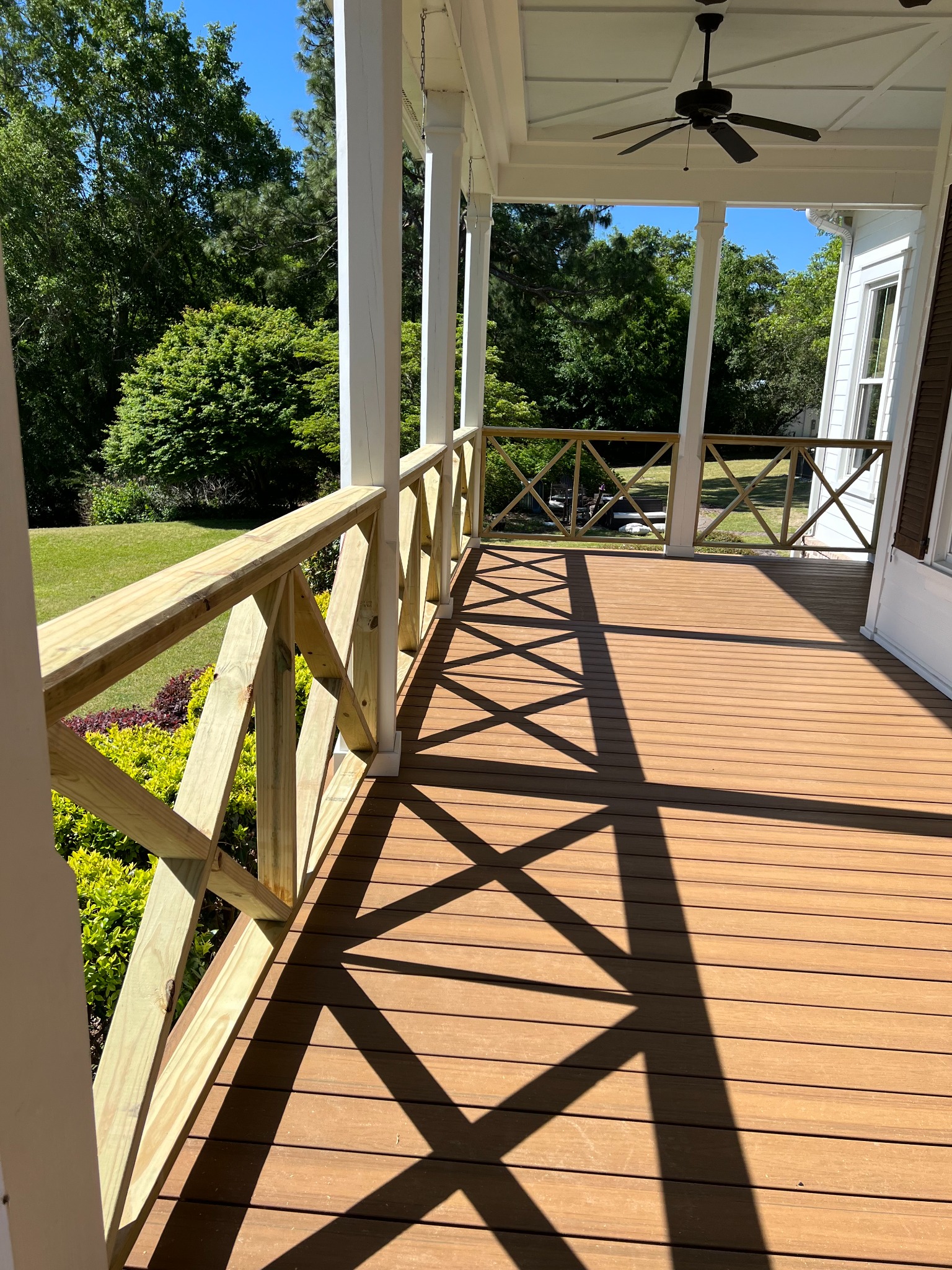 Covered porch with composite decking, cross-braced railings, columns, and coffered ceiling