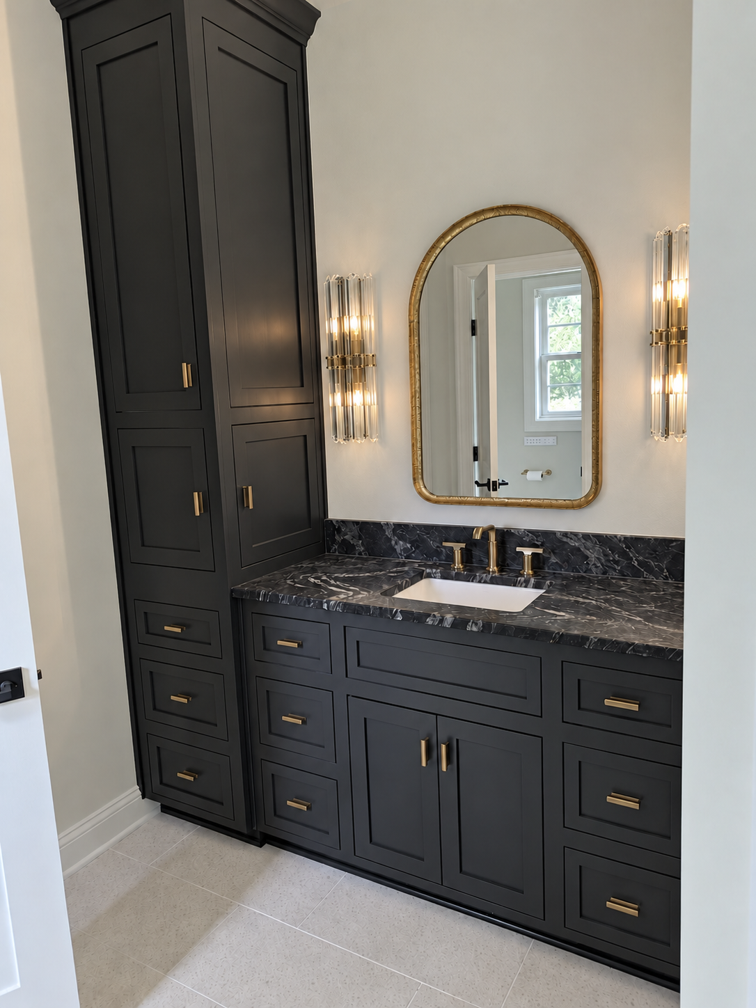 Black custom bathroom vanity with integrated storage, dark stone, brass hardware, and arched mirror