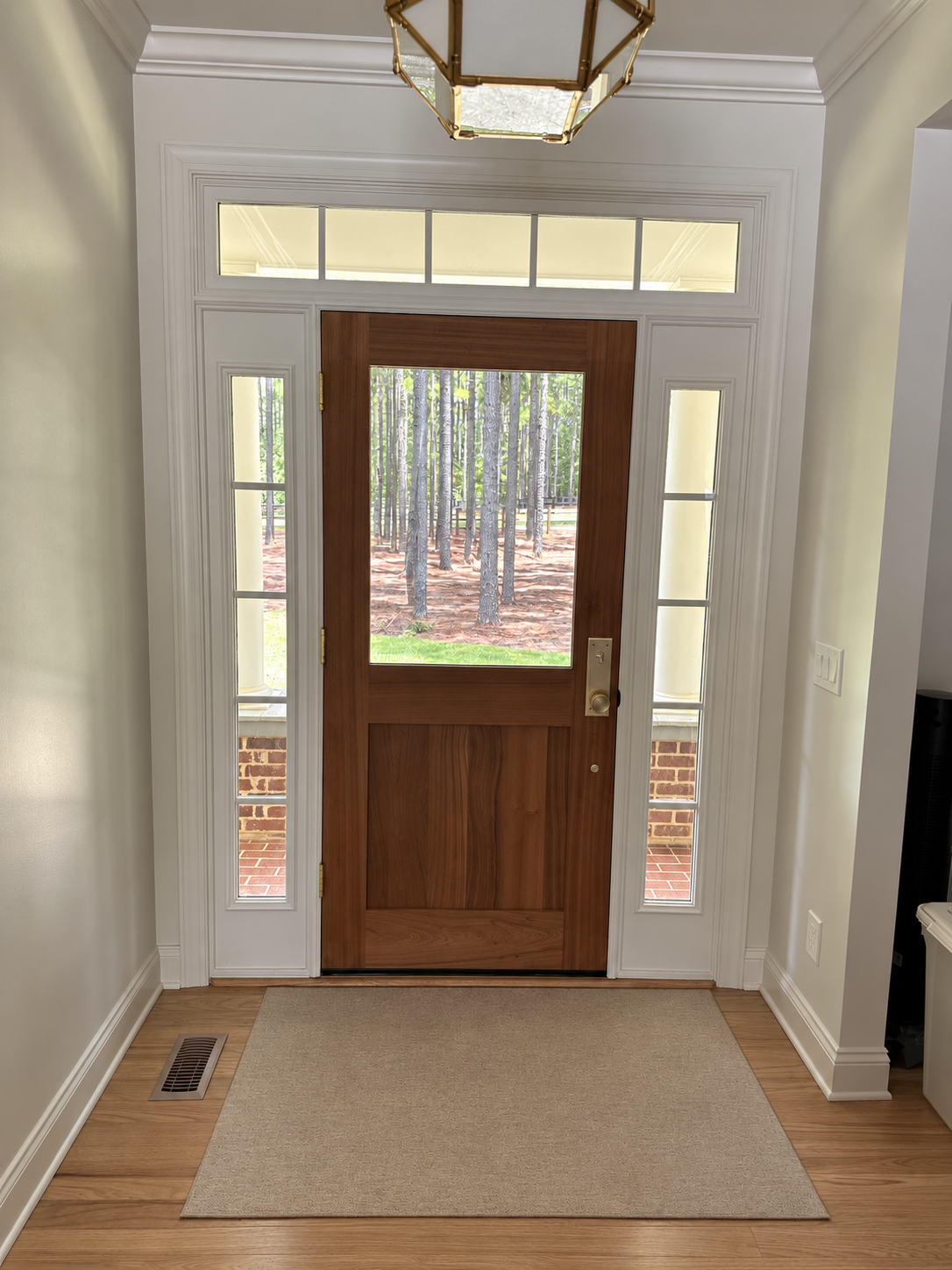 Mahogany entry door framed by detailed white millwork, sidelights, and transom