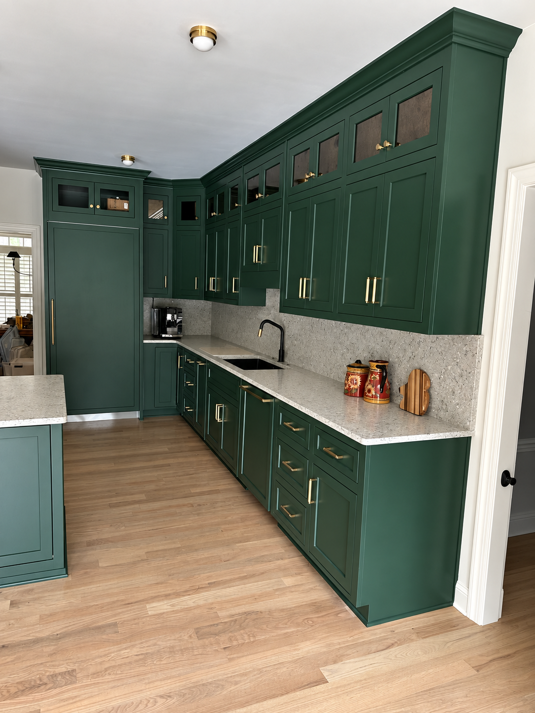 Emerald green full-height cabinetry with brass hardware and stone surfaces