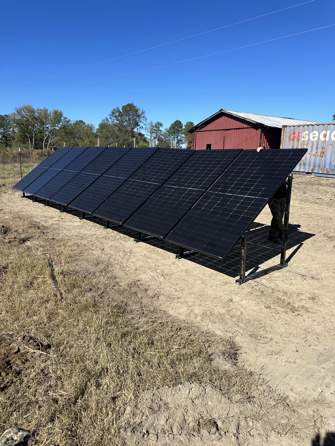 Ground-mounted solar panels installed beside an agricultural building